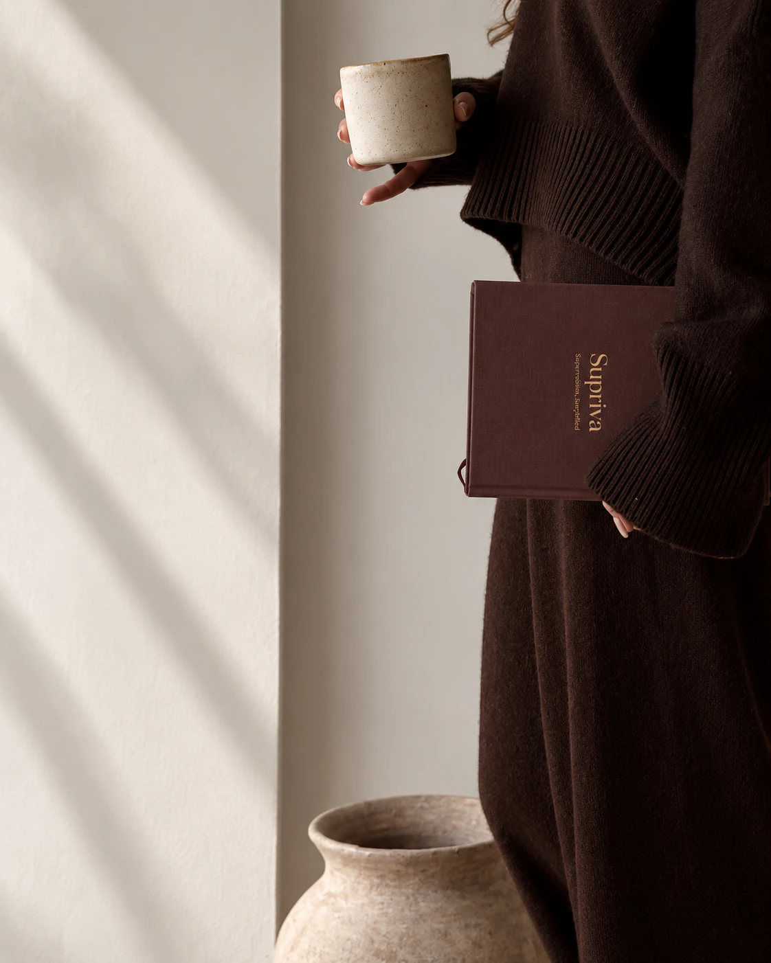 A supervisor holding a Supriva journal and a cup in morning light